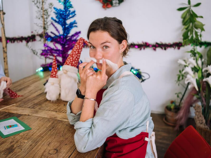 A woman holding fluffy white yarn to her face as a fake moustache